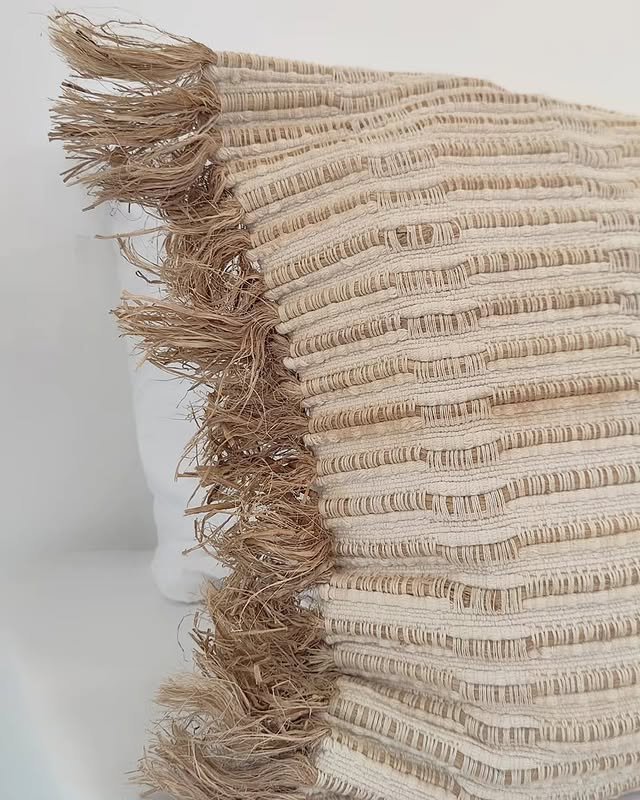 Close-up of a woven raffia-fringed cushion